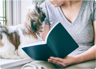Vrouw met een boek en een hond naast haar